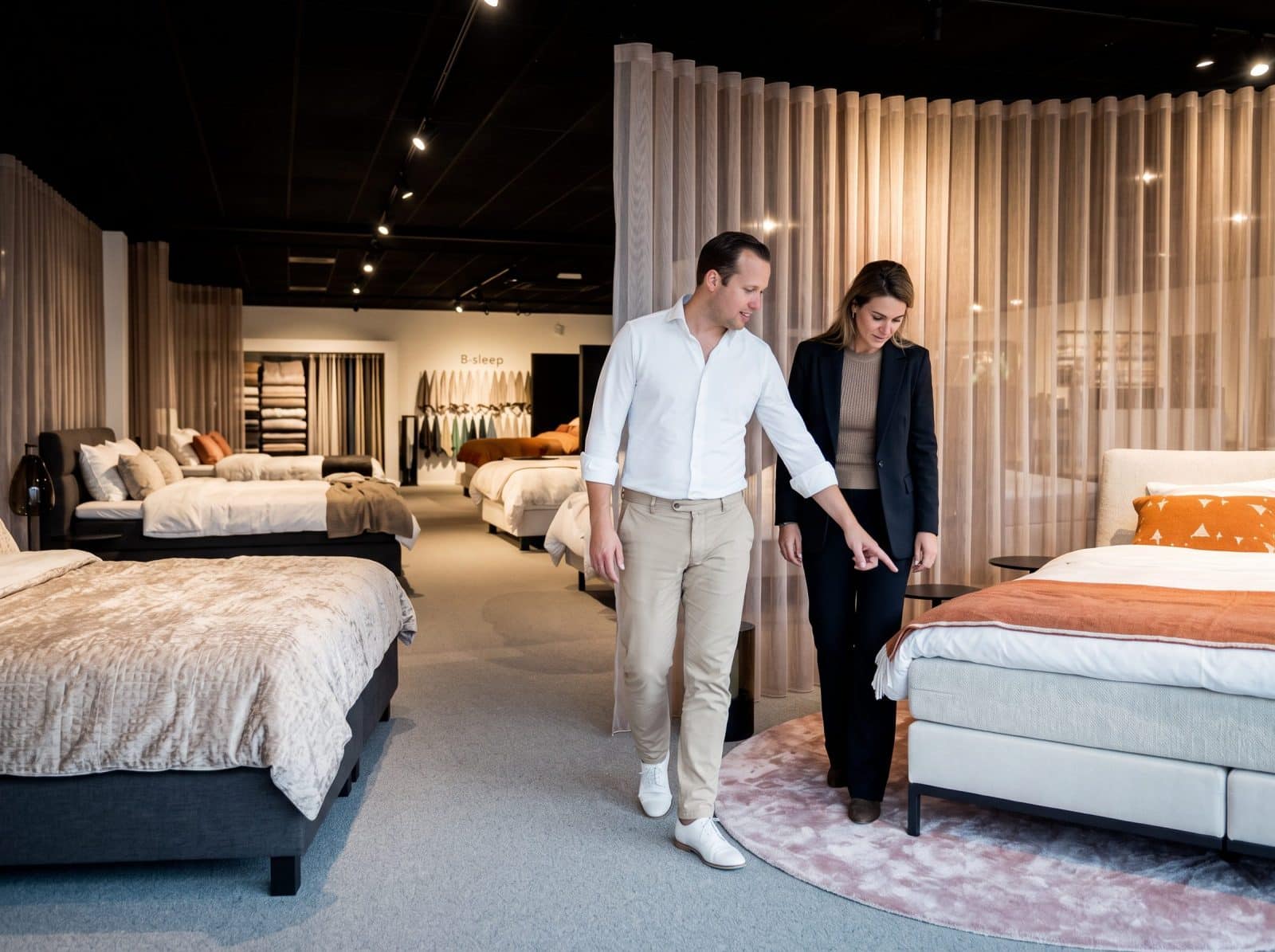 Adviseur van Grisar Slaapcomfort en klant wandelen langs bedden in de ruime toonzaal
