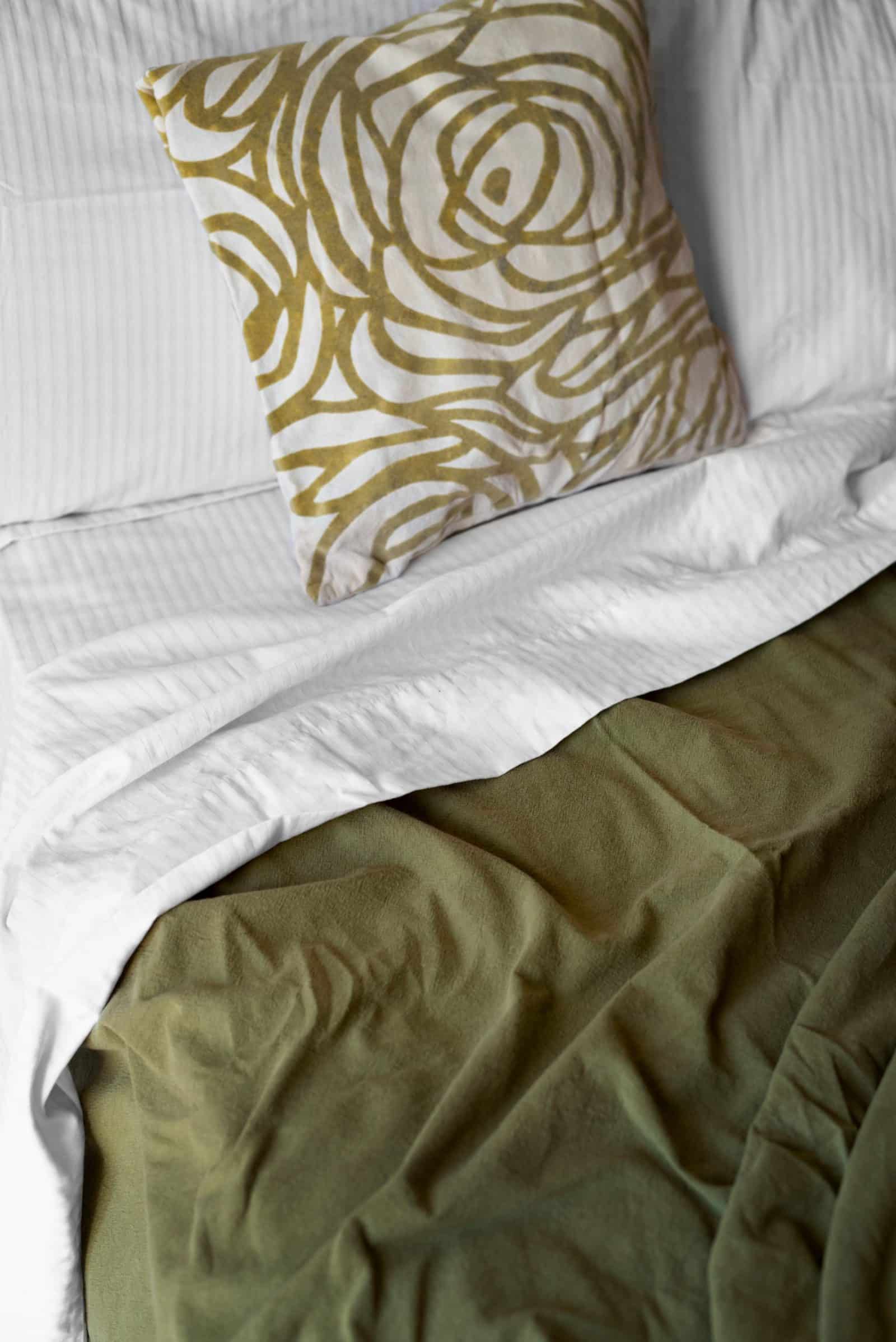 Close-up van wit en olijfgroen beddengoed met een kussen met gouden bloempatroon