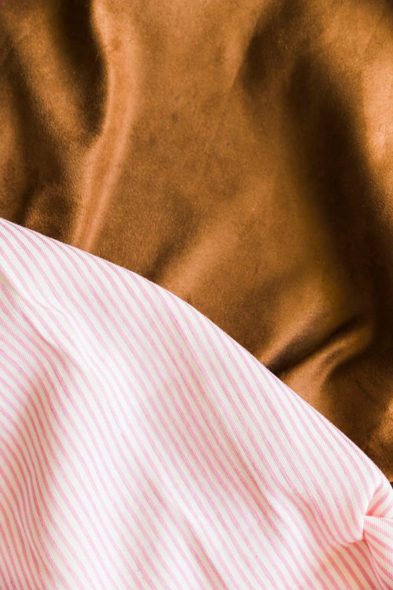 Close-up van glanzende bruine stof naast roze gestreept beddengoed
