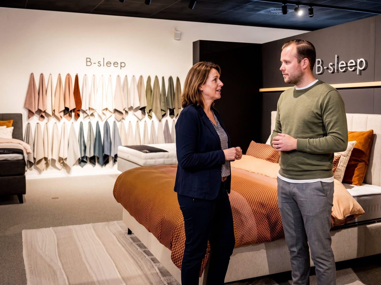 Adviseur en klant praten bij een bed in de B-Sleep hoek van de toonzaal