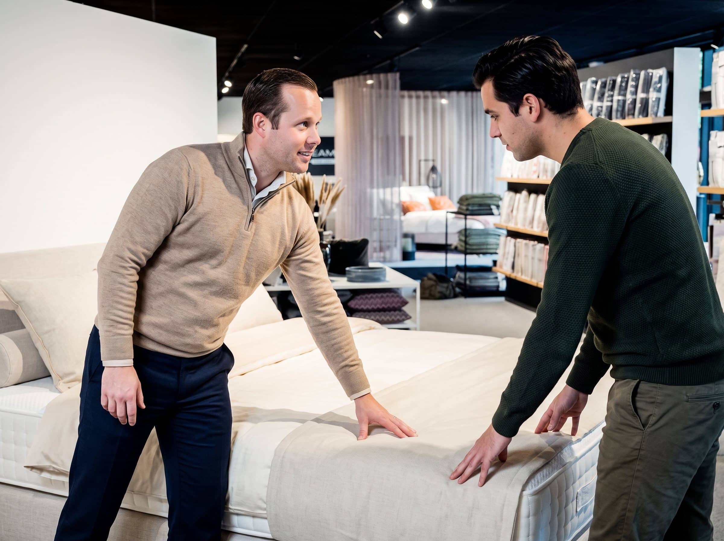 Adviseur van Grisar Slaapcomfort en klant voelen aan een bed in de toonzaal
