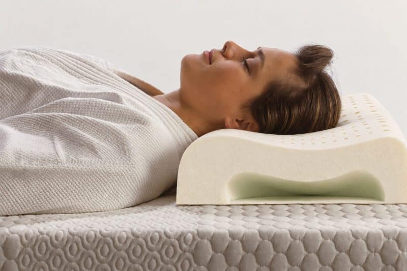Vrouw ligt op haar rug met haar hoofd op een ergonomisch latex nekkussen