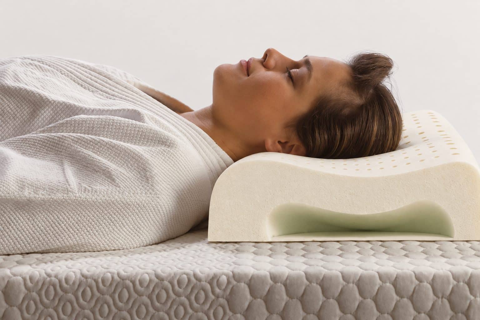 Vrouw ligt op haar rug met haar hoofd op een ergonomisch latex nekkussen