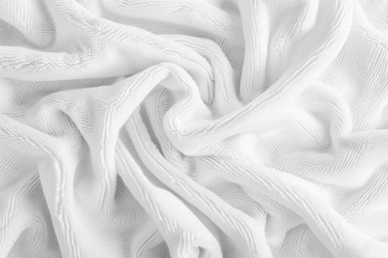 Close-up van wit, gestructureerd bedtextiel dat in plooien ligt