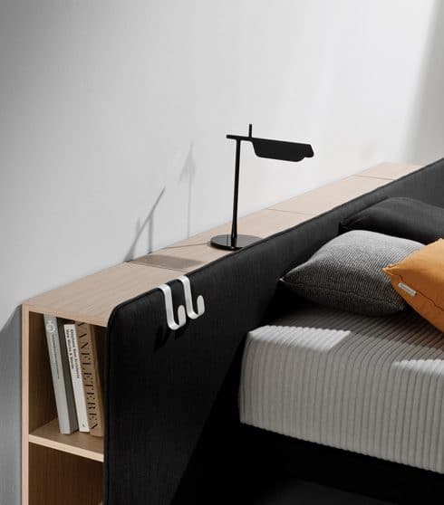 Zwart hoofdbord met leeslamp en boeken, met een grijze matras